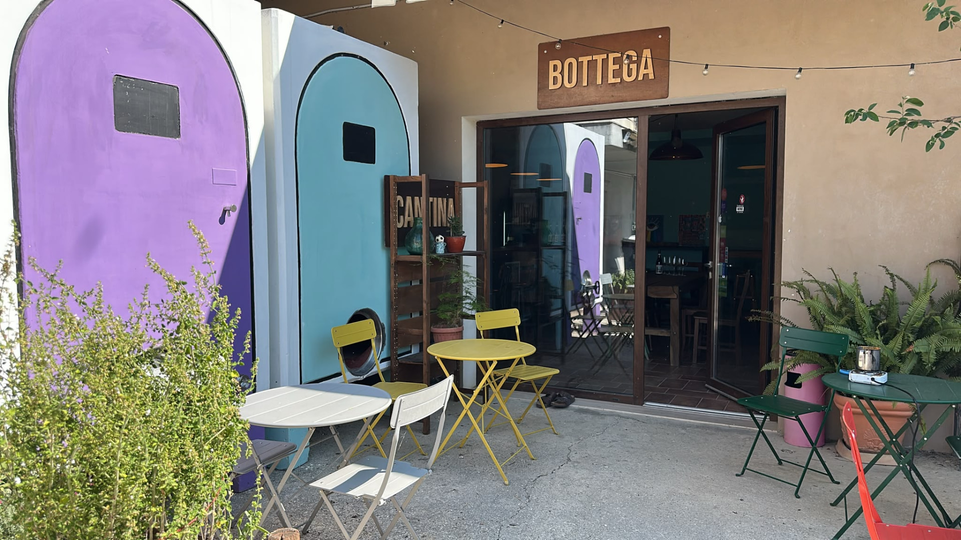 Bottega entrance of the Bossanova winery with arched purple and blue doors and yellow bistro furniture